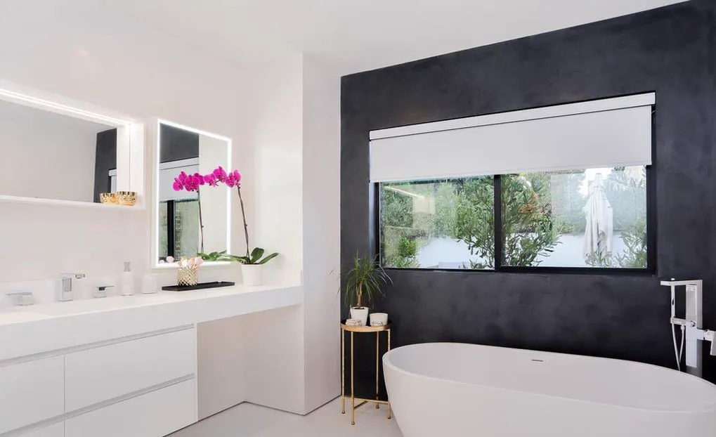 Freestanding tub in front of a dark accent wall with a window