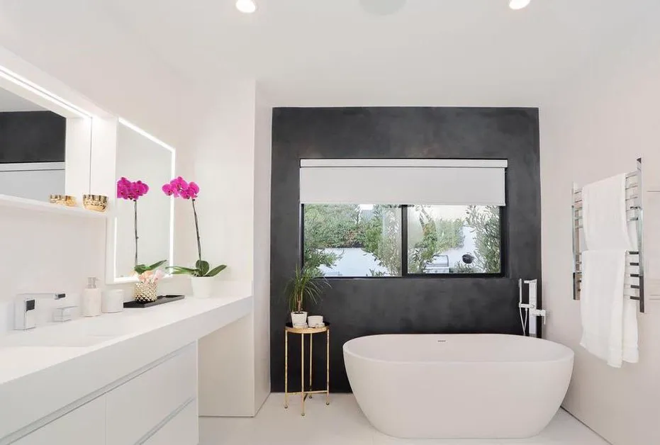 Primary bathroom with a freestanding tub, vanity, and dark accent wall