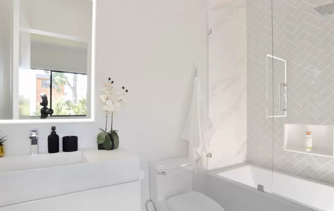 White bathroom with a tub, glass shower, and lit mirror