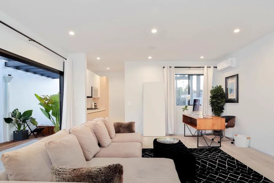 Living room with a sectional sofa, desk, and large window to the garden