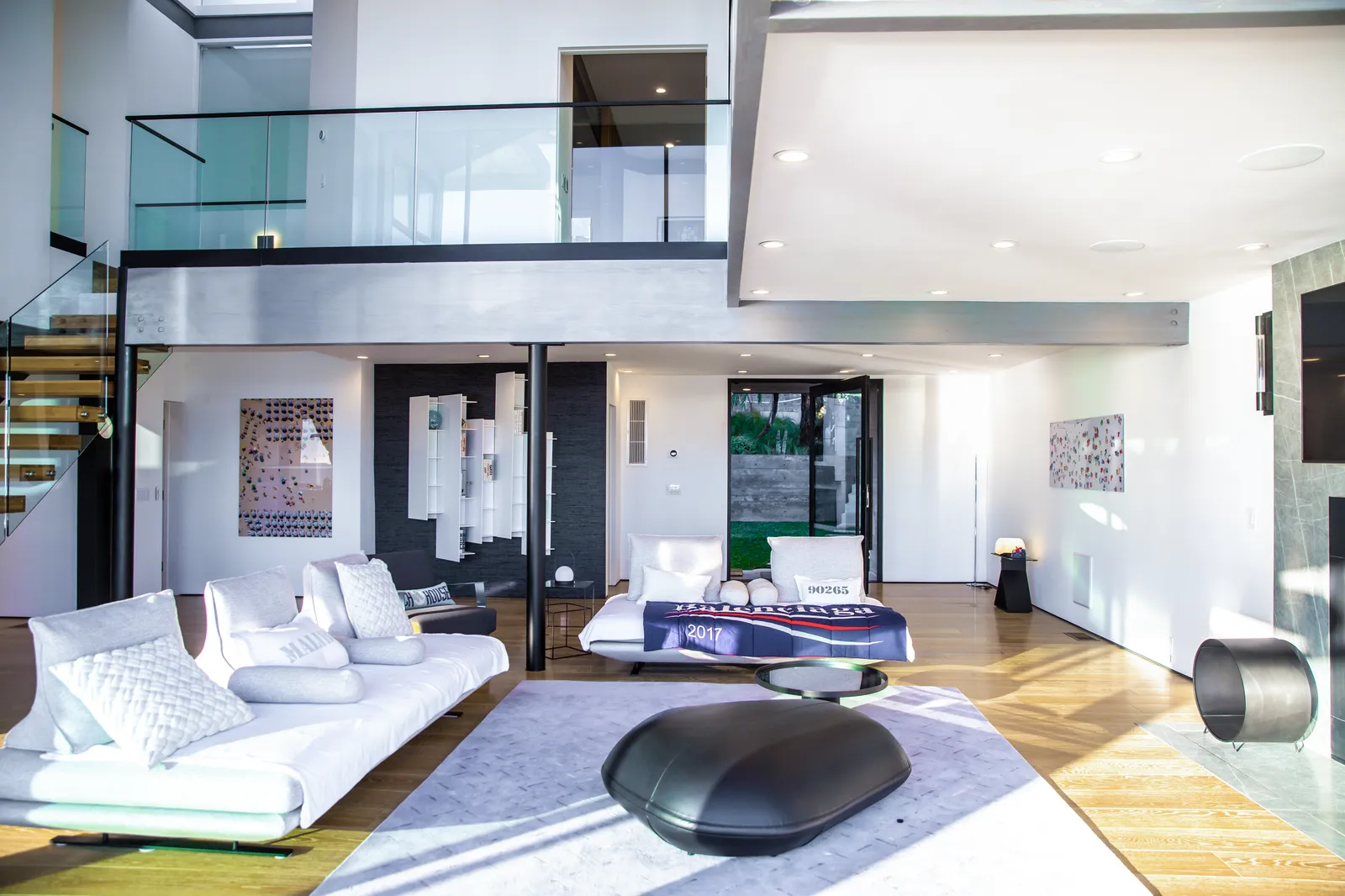 Living room with white sofas beneath a glass mezzanine