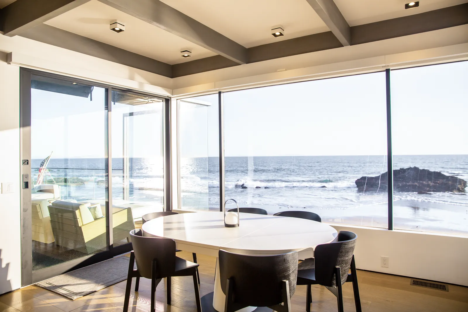 Dining table in a glass corner overlooking the ocean and rocks