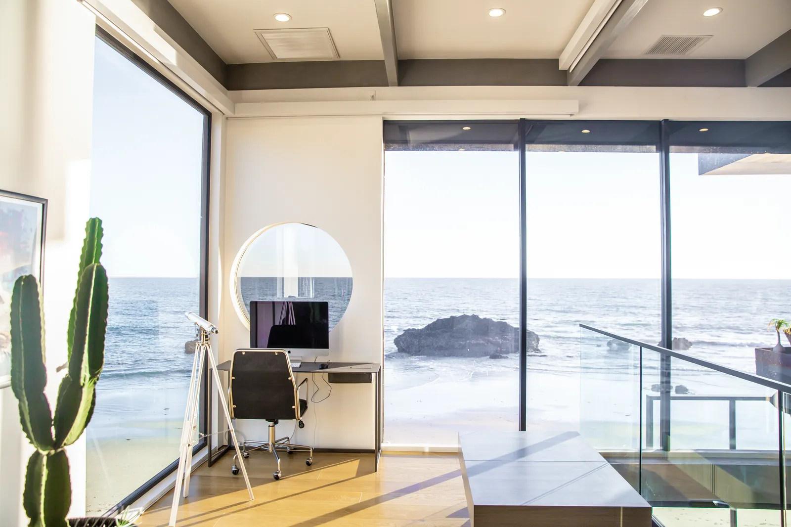 Desk in a glass corner with ocean views and a cactus