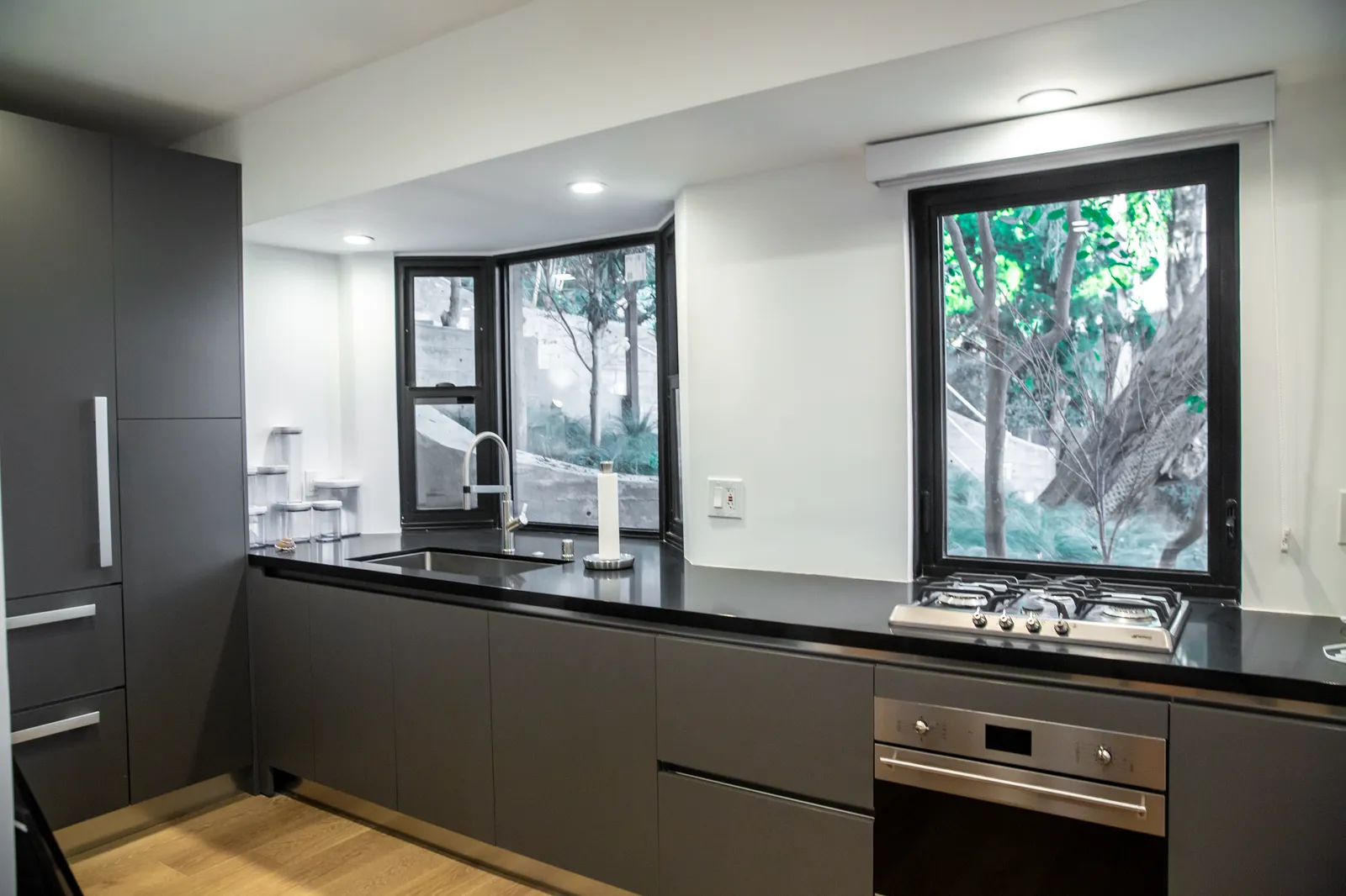 Dark kitchen run with black counters and windows to the garden