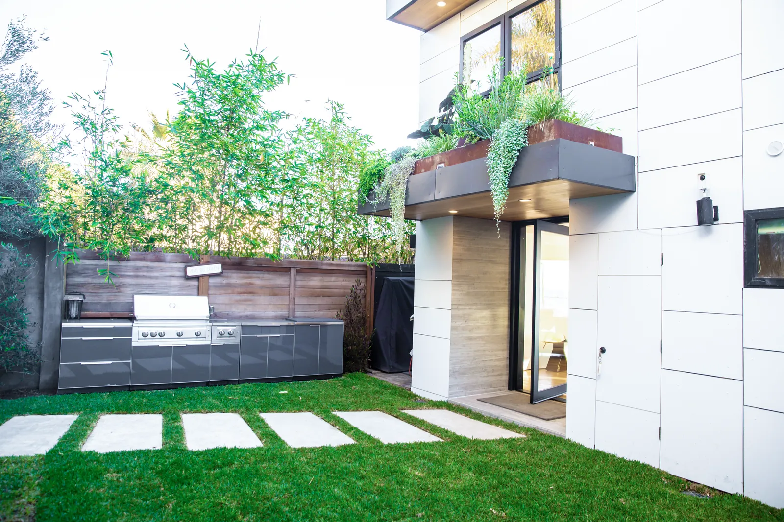 Side yard with a lawn, outdoor kitchen, and white panel facade