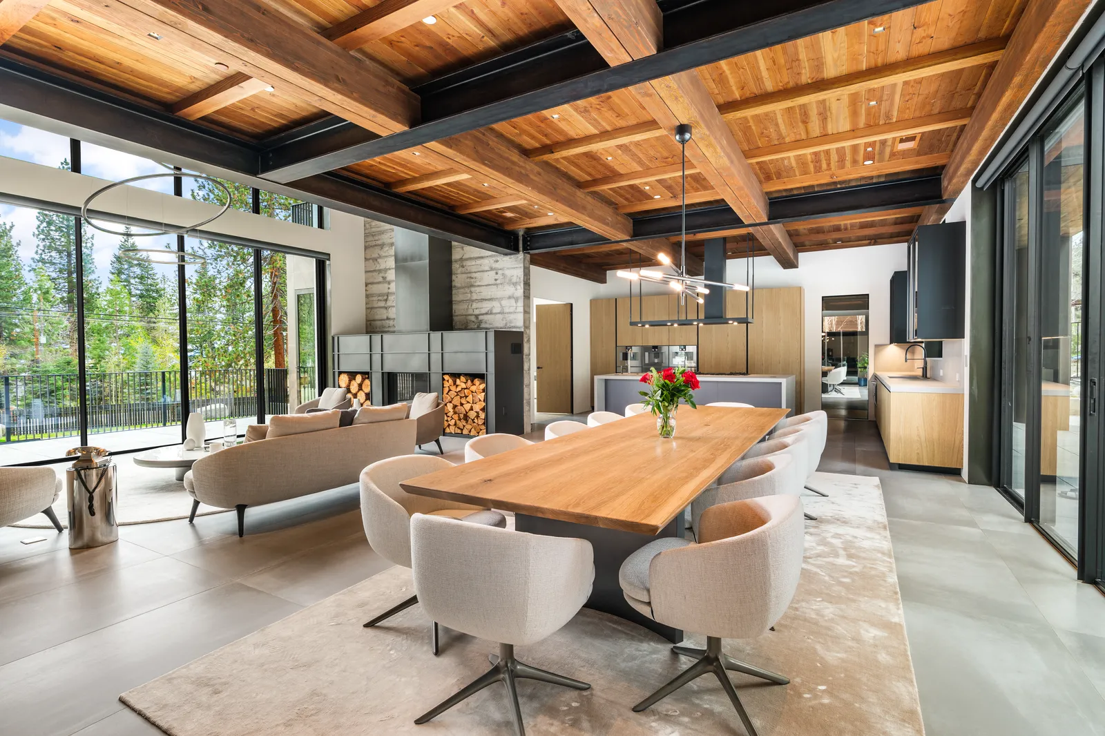 Great room with a timber ceiling, live-edge dining table, and glass walls to the trees
