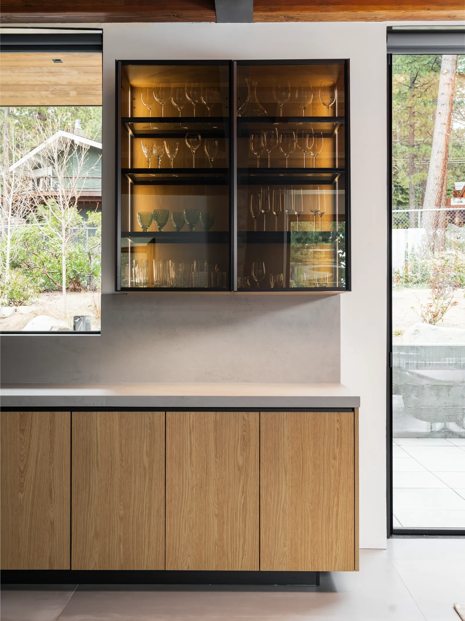 Bar with lit glass-front cabinets above wood base cabinets