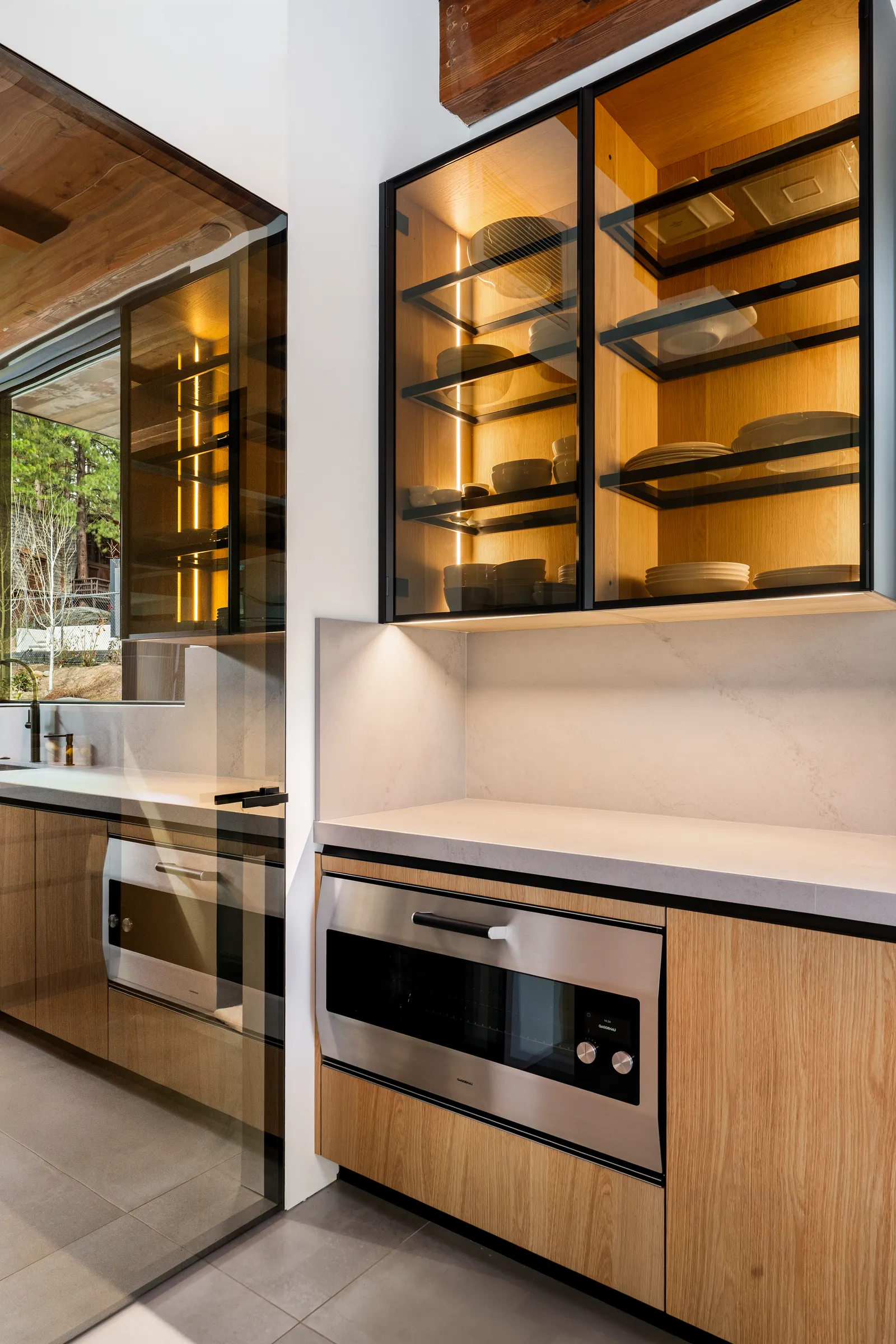 Glass-front cabinets above a built-in oven and microwave drawer