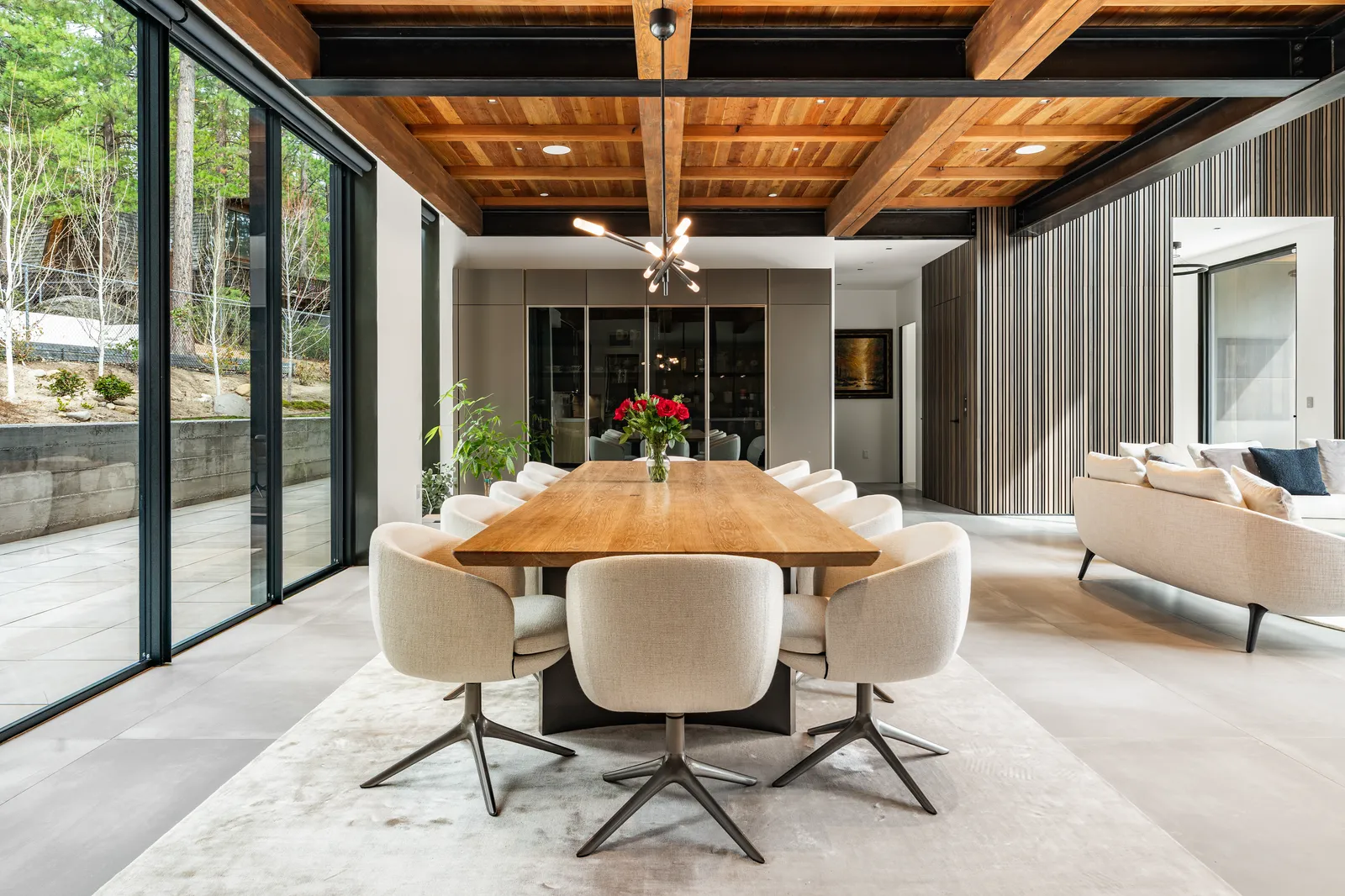 Dining area with a wood table and white swivel chairs under a timber ceiling