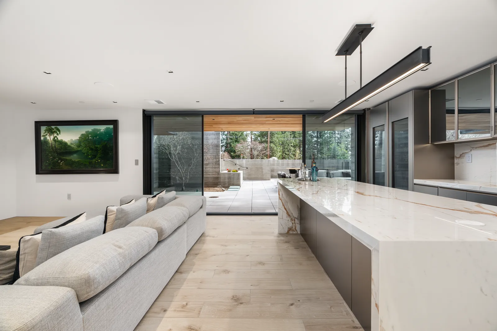 Lower-level lounge with a long sofa and a bar with a stone waterfall counter