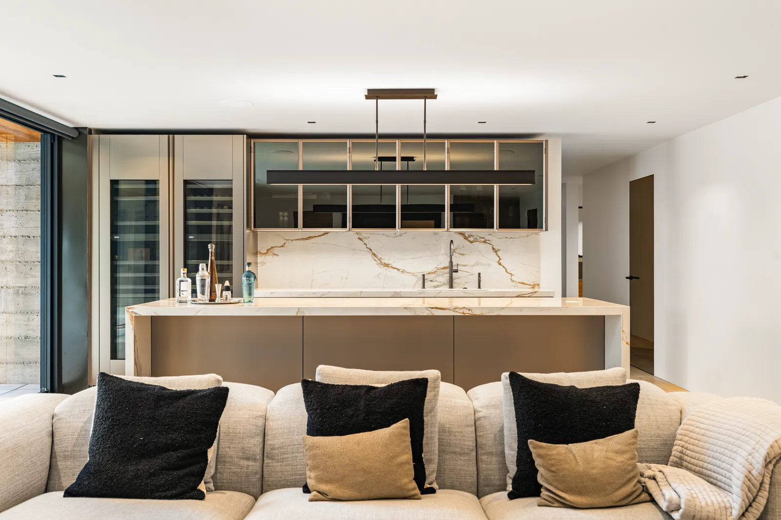 Bar with a gold-veined stone backsplash and counter, wine storage, and glass-front cabinets