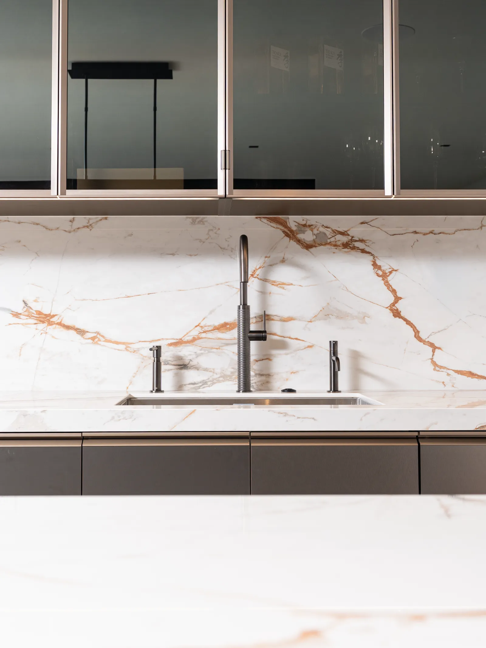 Bar sink and faucet against a gold-veined stone backsplash