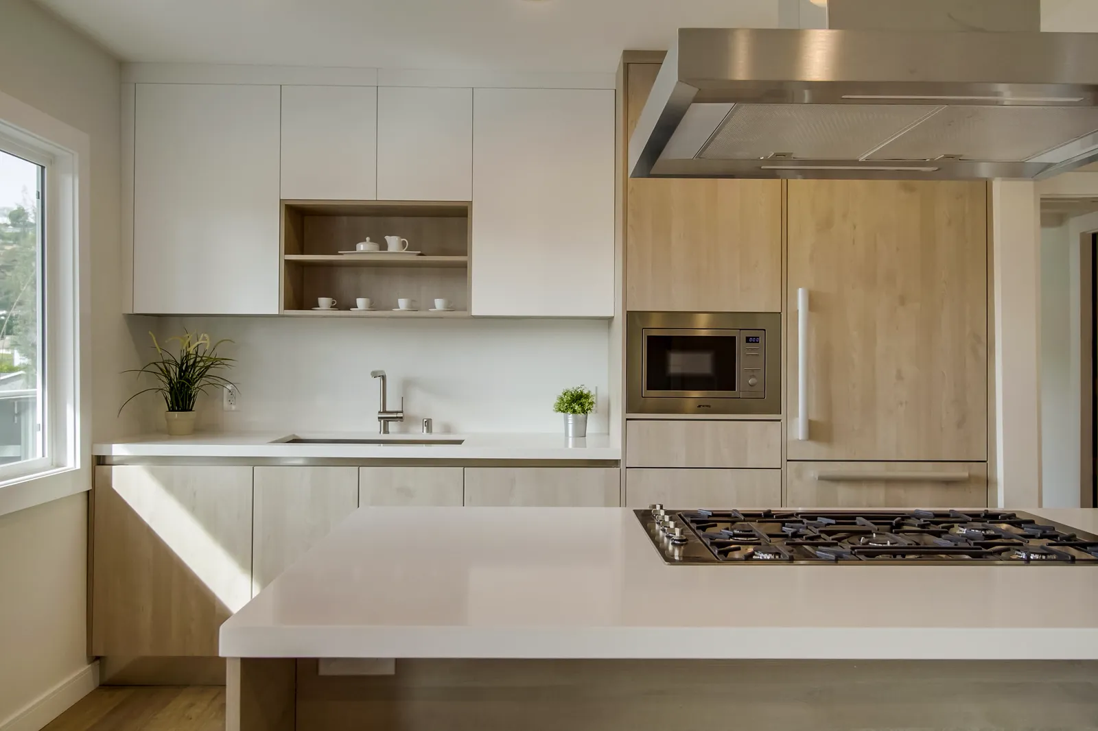 Renovated kitchen with light oak and white cabinetry, a quartz island, and a stainless hood