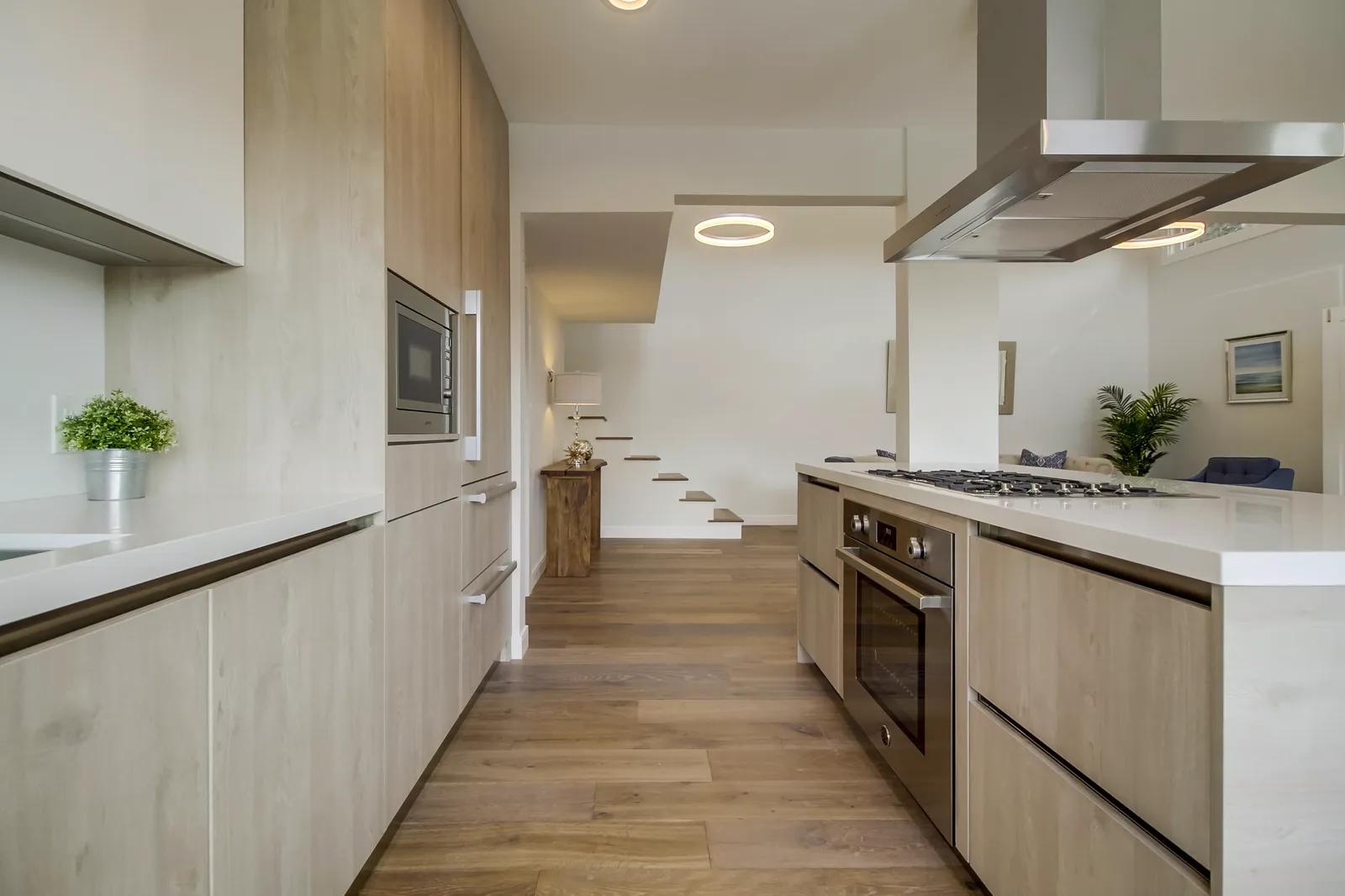 Galley view of the kitchen with integrated appliances and a ring pendant light