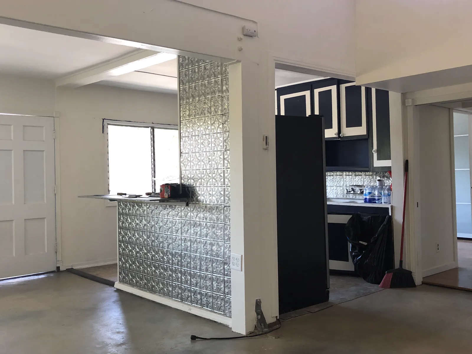 Before the renovation: the original kitchen behind a wall with a tin backsplash and dark cabinets