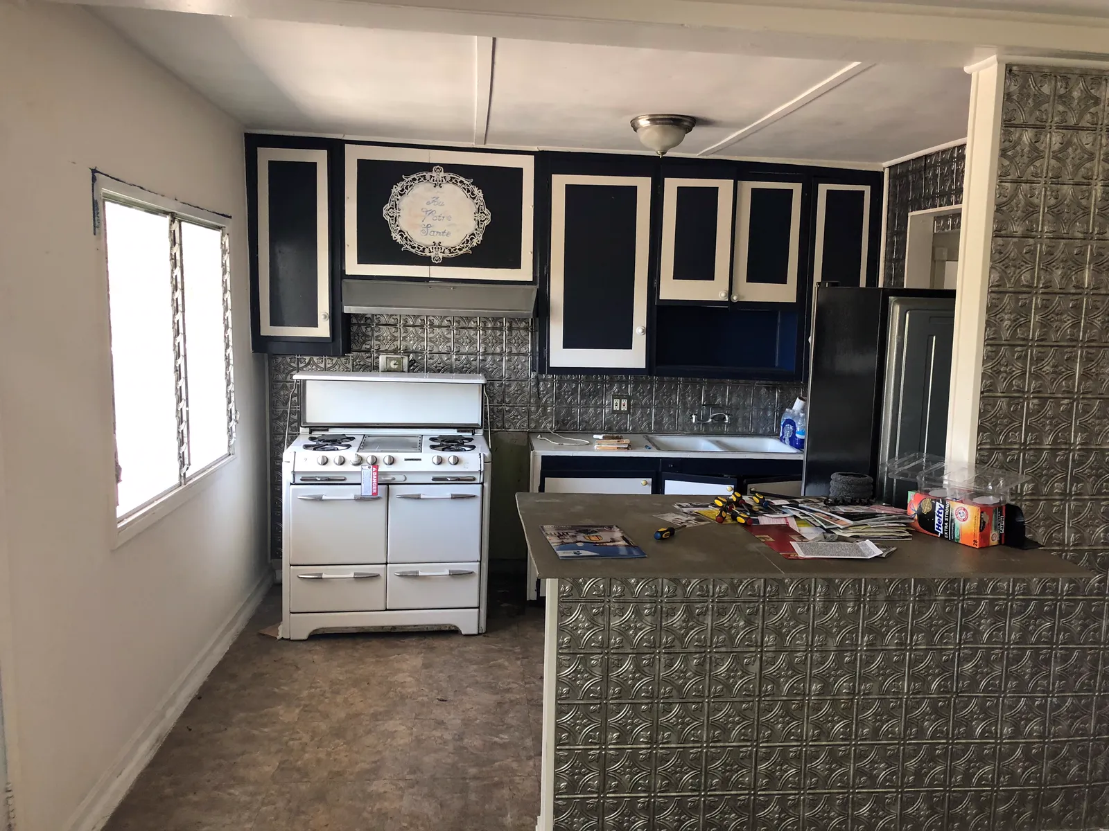 Before the renovation: the original closed kitchen with a white range and decorative tin panels